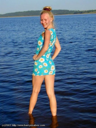 Красивая девушка у реки показывает грудь и бритую киску